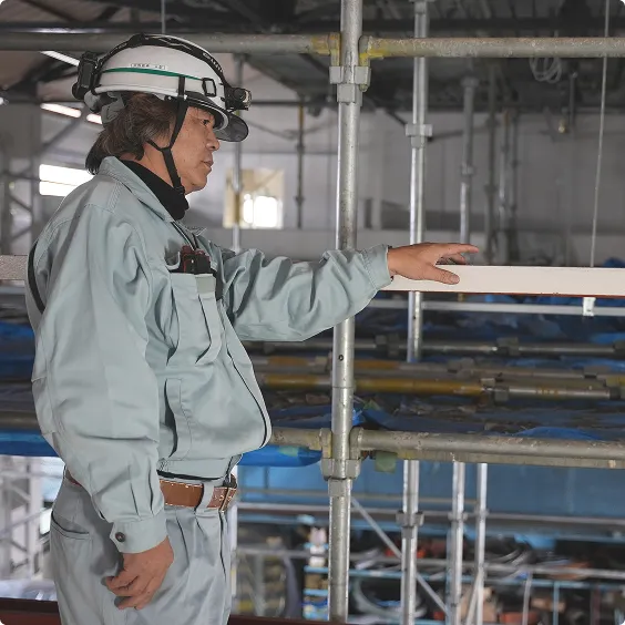 足場の上で指示を出すヘルメット姿の作業員