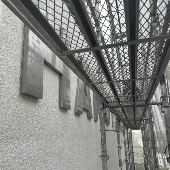建物の外壁に設置された切り文字看板と手前の足場