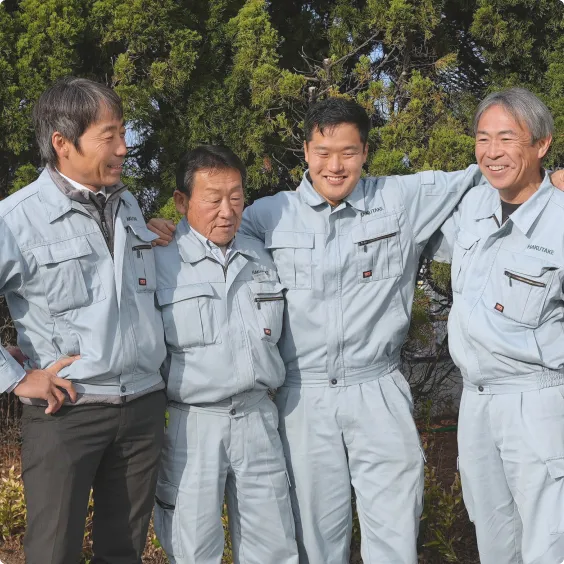 肩を組んで笑顔を見せる4人の作業員たちの集合写真